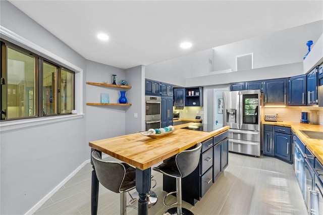 kitchen with butcher block countertops, blue cabinets, open shelves, and appliances with stainless steel finishes