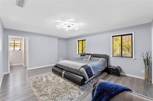 bedroom with visible vents, baseboards, and wood finished floors