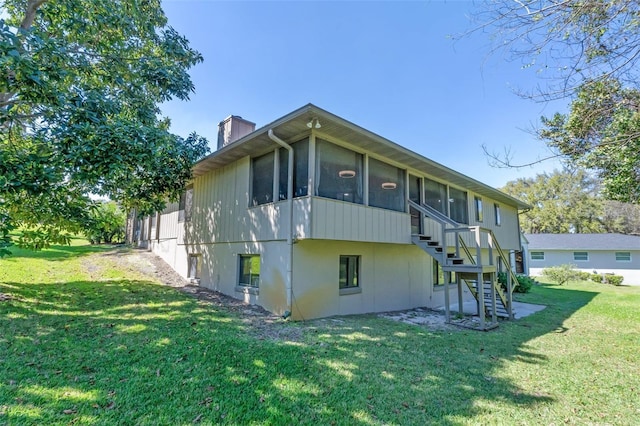 view of property exterior with stairway, a lawn, a chimney, and a sunroom