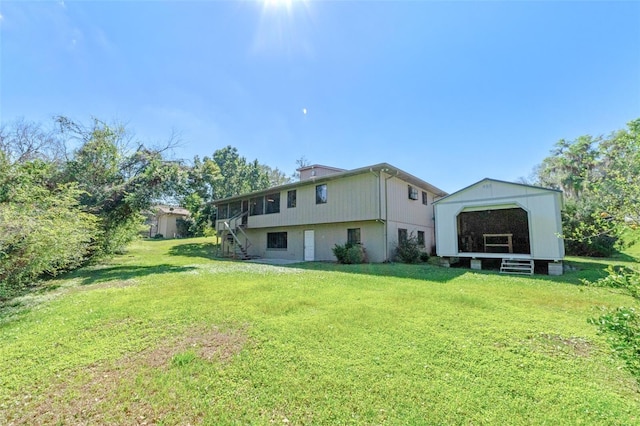 rear view of property featuring stairs, an outbuilding, and a yard