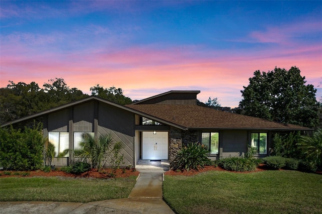 mid-century home with a lawn and roof with shingles