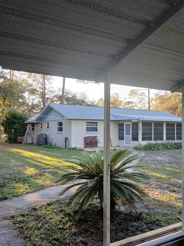 view of front of home featuring a front yard, cooling unit, and a sunroom