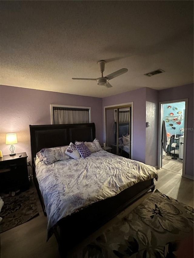 bedroom featuring a textured ceiling, visible vents, a ceiling fan, a closet, and light wood-type flooring