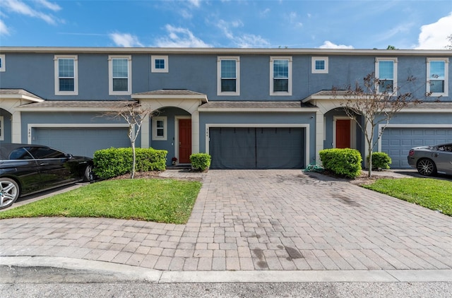 view of front facade with a garage, decorative driveway, and stucco siding