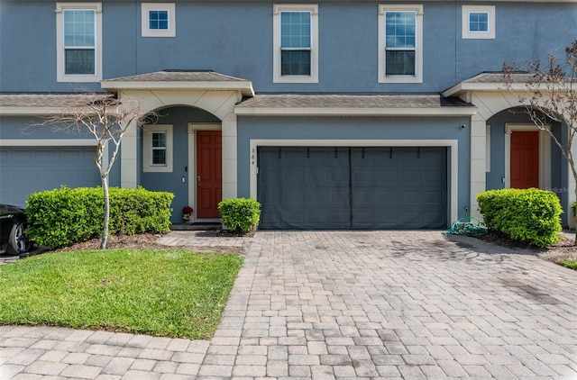 view of front of property featuring an attached garage, decorative driveway, and stucco siding