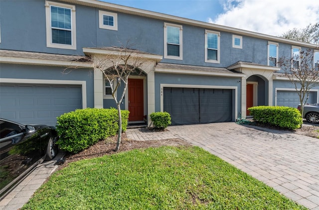 multi unit property with decorative driveway, an attached garage, and stucco siding