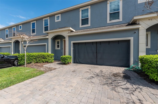 view of front facade with a garage, decorative driveway, and stucco siding