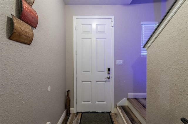 entryway with baseboards, wood finished floors, and a textured wall