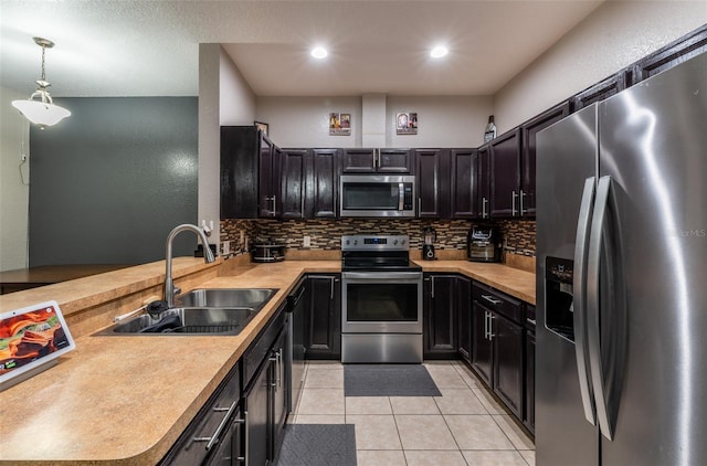 kitchen featuring decorative light fixtures, a peninsula, stainless steel appliances, light countertops, and a sink