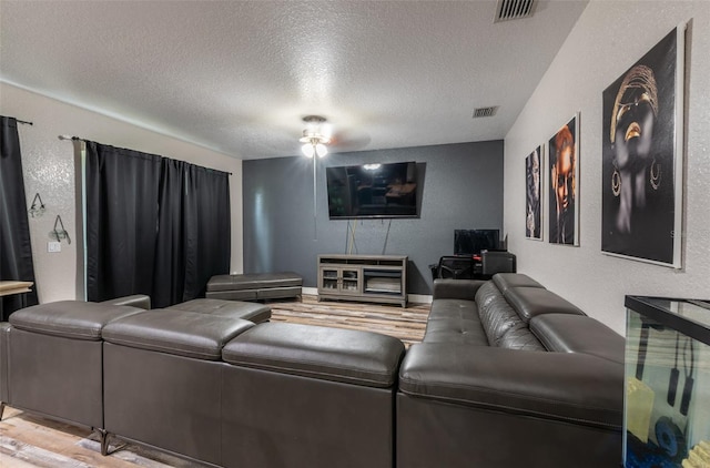 living area featuring baseboards, visible vents, a textured wall, a textured ceiling, and light wood-style floors