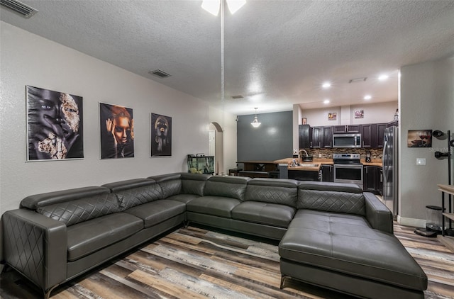 living room with arched walkways, wood finished floors, and visible vents