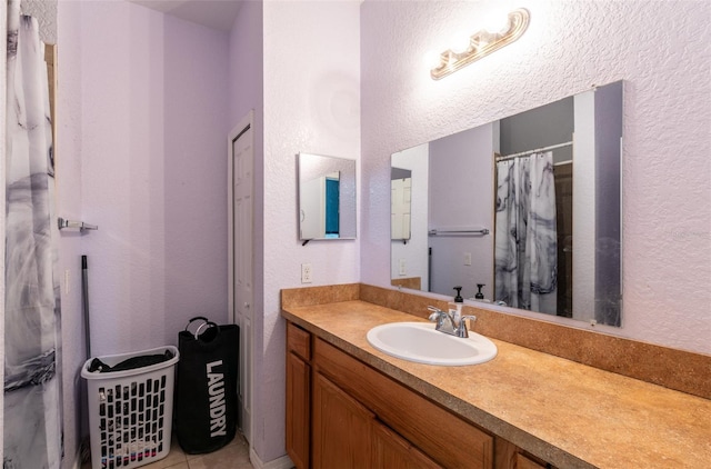 full bathroom with a textured wall, a shower with shower curtain, and vanity