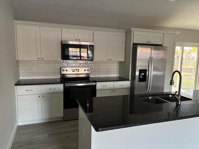 kitchen featuring dark wood-style flooring, a sink, white cabinetry, appliances with stainless steel finishes, and tasteful backsplash