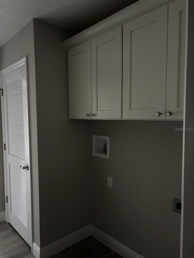 laundry room featuring washer hookup, cabinet space, a textured ceiling, wood finished floors, and baseboards