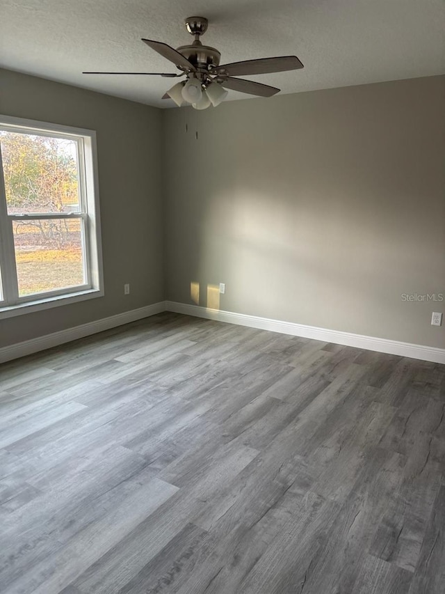 spare room with a ceiling fan, a textured ceiling, baseboards, and wood finished floors