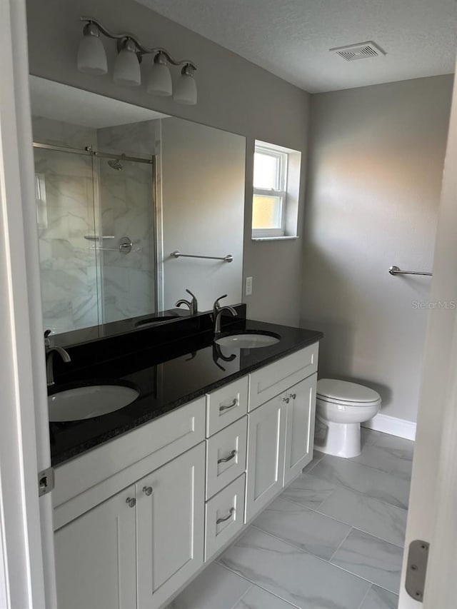 bathroom featuring marble finish floor, a sink, visible vents, and a shower stall