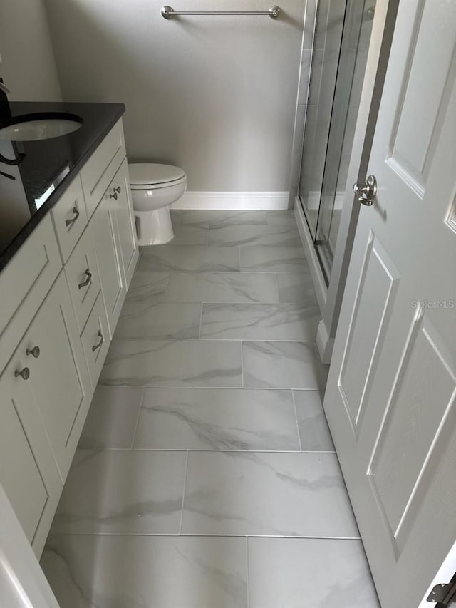 bathroom featuring a stall shower, baseboards, toilet, marble finish floor, and vanity