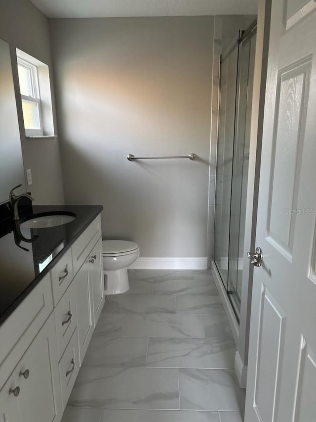 bathroom with baseboards, toilet, marble finish floor, vanity, and a shower stall