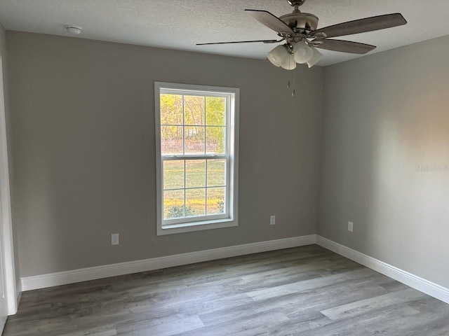 unfurnished room with a ceiling fan, baseboards, a textured ceiling, and light wood finished floors