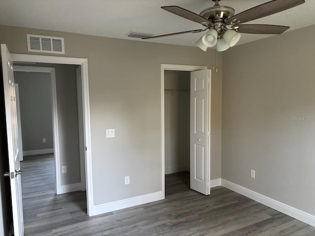 unfurnished bedroom with dark wood-type flooring, visible vents, and baseboards