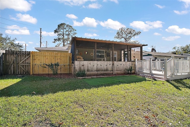 back of house featuring a wooden deck, a yard, fence, and a gate