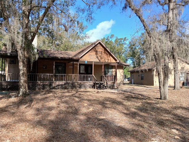 view of front of home with a porch and log veneer siding