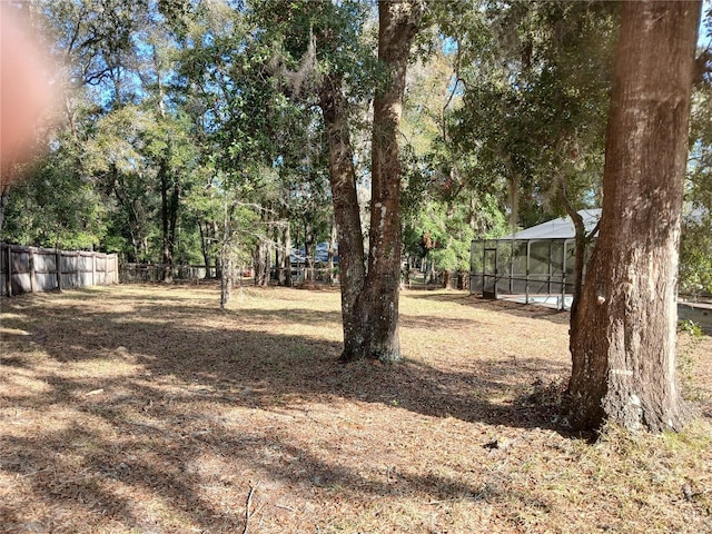 view of yard with glass enclosure and fence