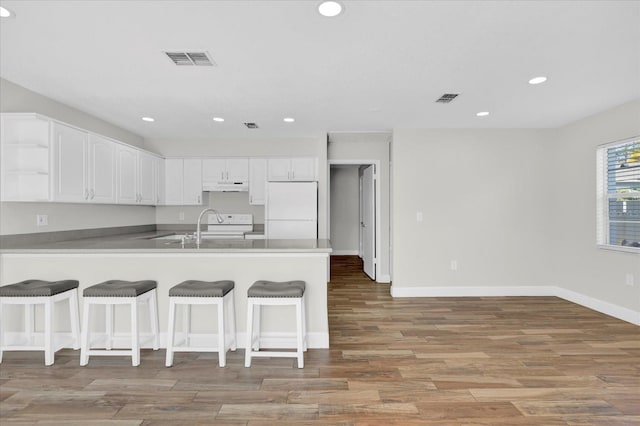 kitchen featuring white appliances, visible vents, under cabinet range hood, and white cabinetry