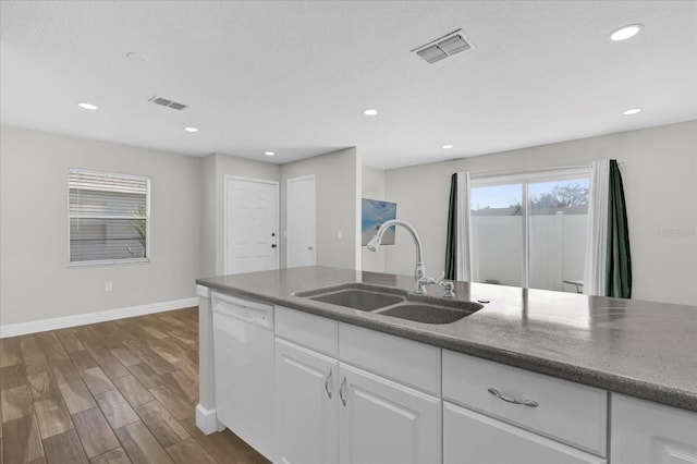 kitchen featuring white dishwasher, a sink, visible vents, white cabinetry, and dark countertops