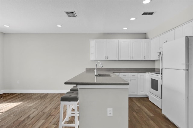 kitchen featuring white appliances, dark countertops, a sink, and white cabinetry