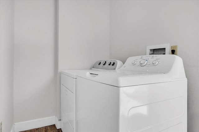 clothes washing area featuring laundry area, baseboards, dark wood finished floors, and washer and dryer