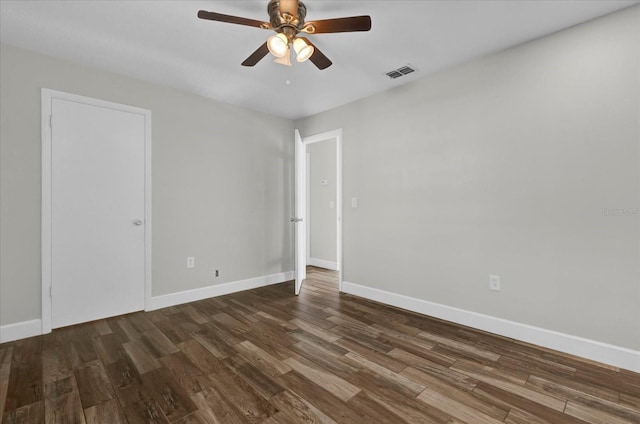 spare room with dark wood-style floors, visible vents, baseboards, and a ceiling fan