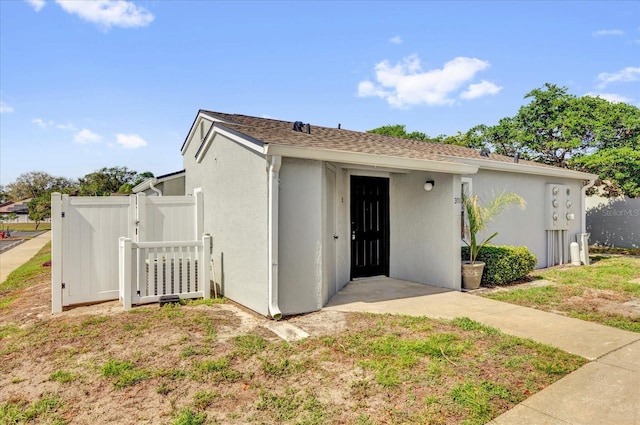 view of front of house with a gate, fence, and stucco siding