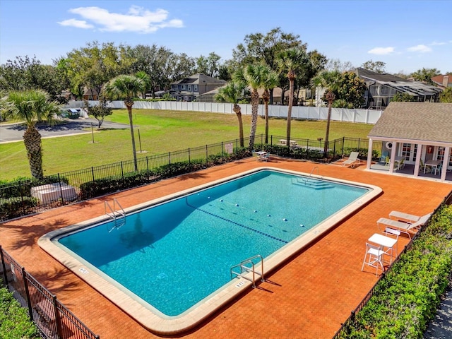 pool featuring a patio area, fence, a lawn, and an outbuilding