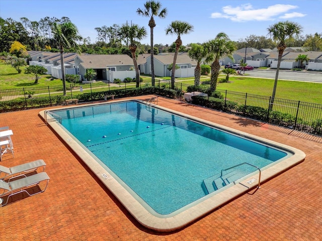 community pool with a patio, a yard, fence, and a residential view