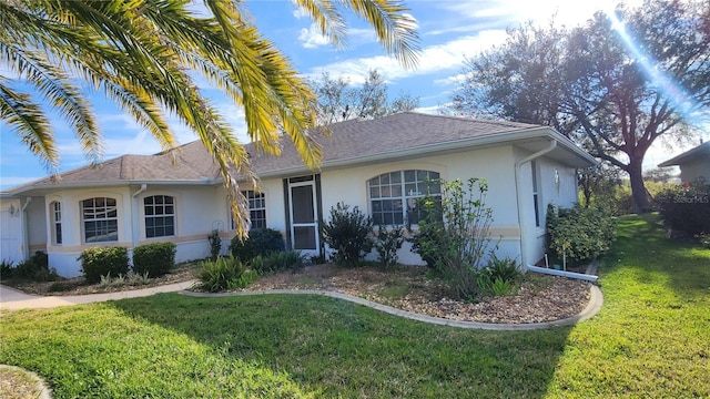 single story home featuring roof with shingles, a front yard, and stucco siding