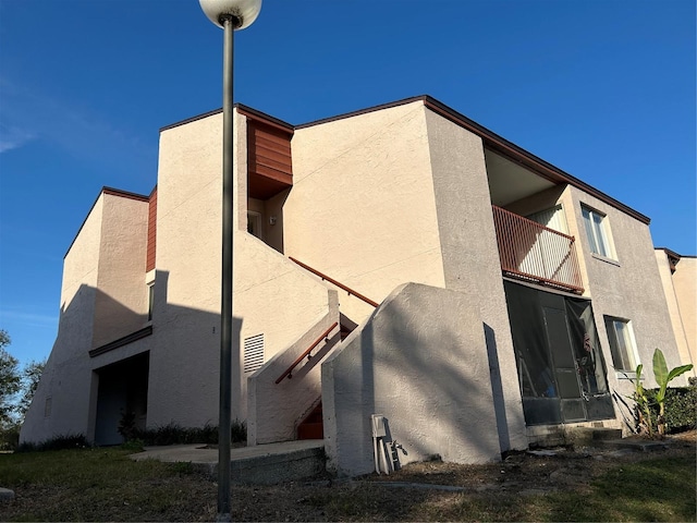 rear view of house featuring a balcony and stucco siding