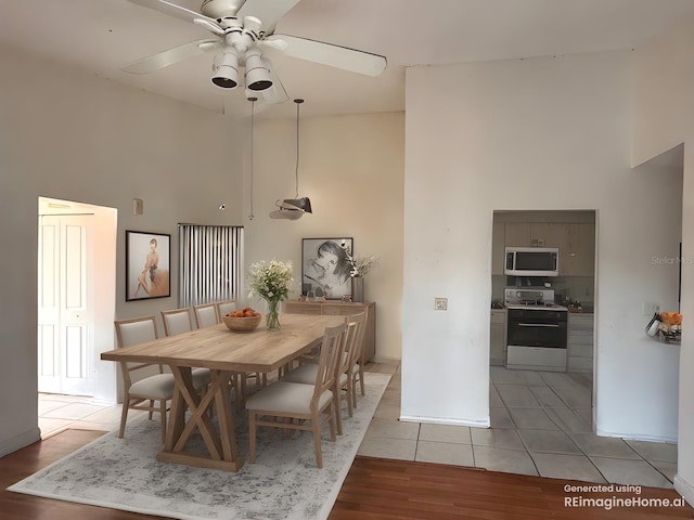 dining room with ceiling fan, a high ceiling, and light tile patterned flooring