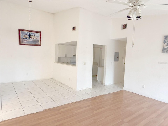 unfurnished room with ceiling fan, visible vents, a towering ceiling, and light wood-style flooring