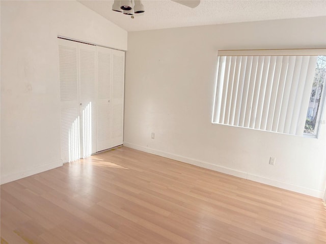 unfurnished bedroom featuring light wood-style floors, a closet, multiple windows, and baseboards