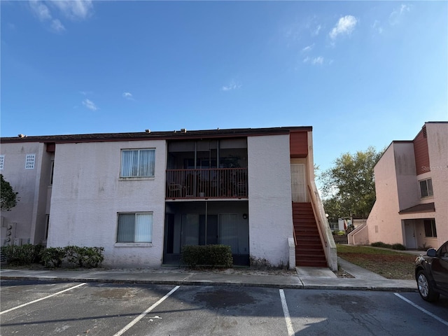 view of property with stairs and uncovered parking