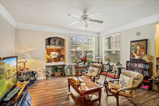 sitting room featuring ceiling fan, baseboards, wood finished floors, and crown molding