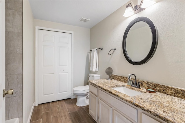 bathroom with toilet, vanity, visible vents, and wood tiled floor