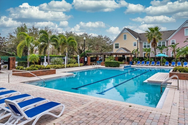 community pool with a patio area and fence