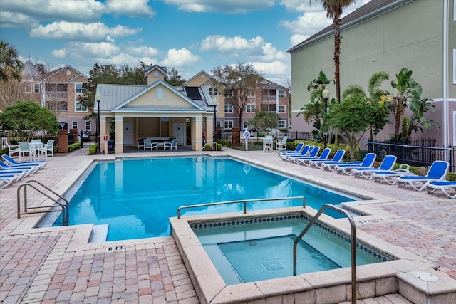 view of pool with a pool with connected hot tub, fence, and a patio