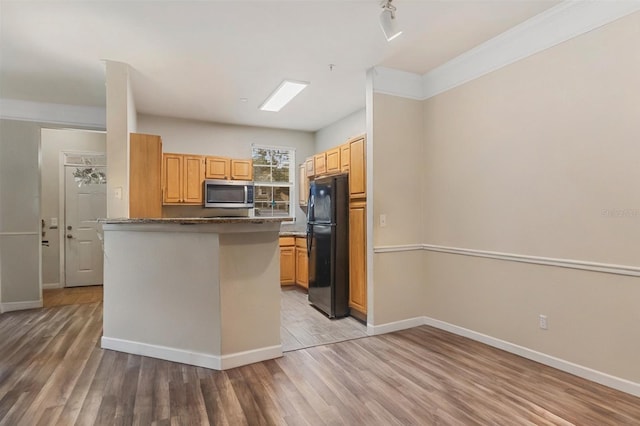 3368 Parkchester Square Blvd Unit 104, Orlando, FL 32835 - kitchen featuring stainless steel microwave, freestanding refrigerator, light wood-style flooring, baseboards, and a peninsula