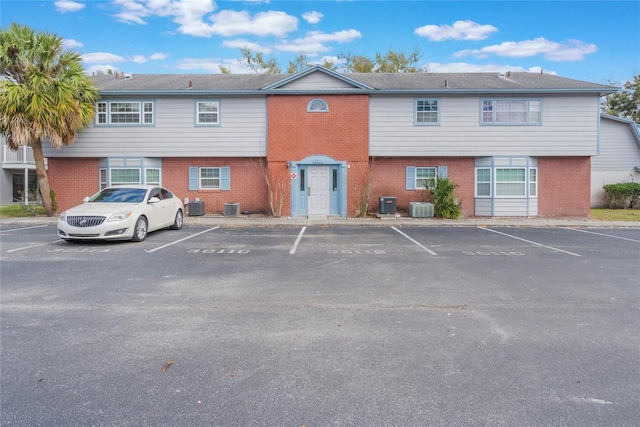 view of property featuring uncovered parking and cooling unit