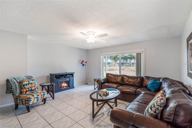 living area featuring light tile patterned floors, a warm lit fireplace, baseboards, and a textured ceiling