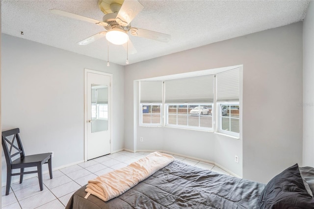 bedroom featuring a textured ceiling, light tile patterned flooring, a ceiling fan, and baseboards