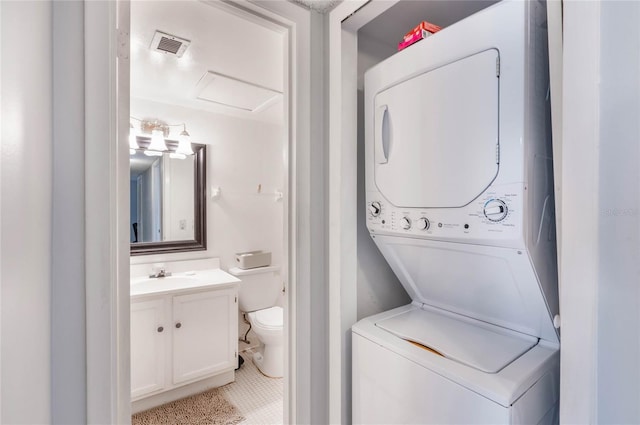 washroom with laundry area, attic access, visible vents, stacked washer and clothes dryer, and a sink